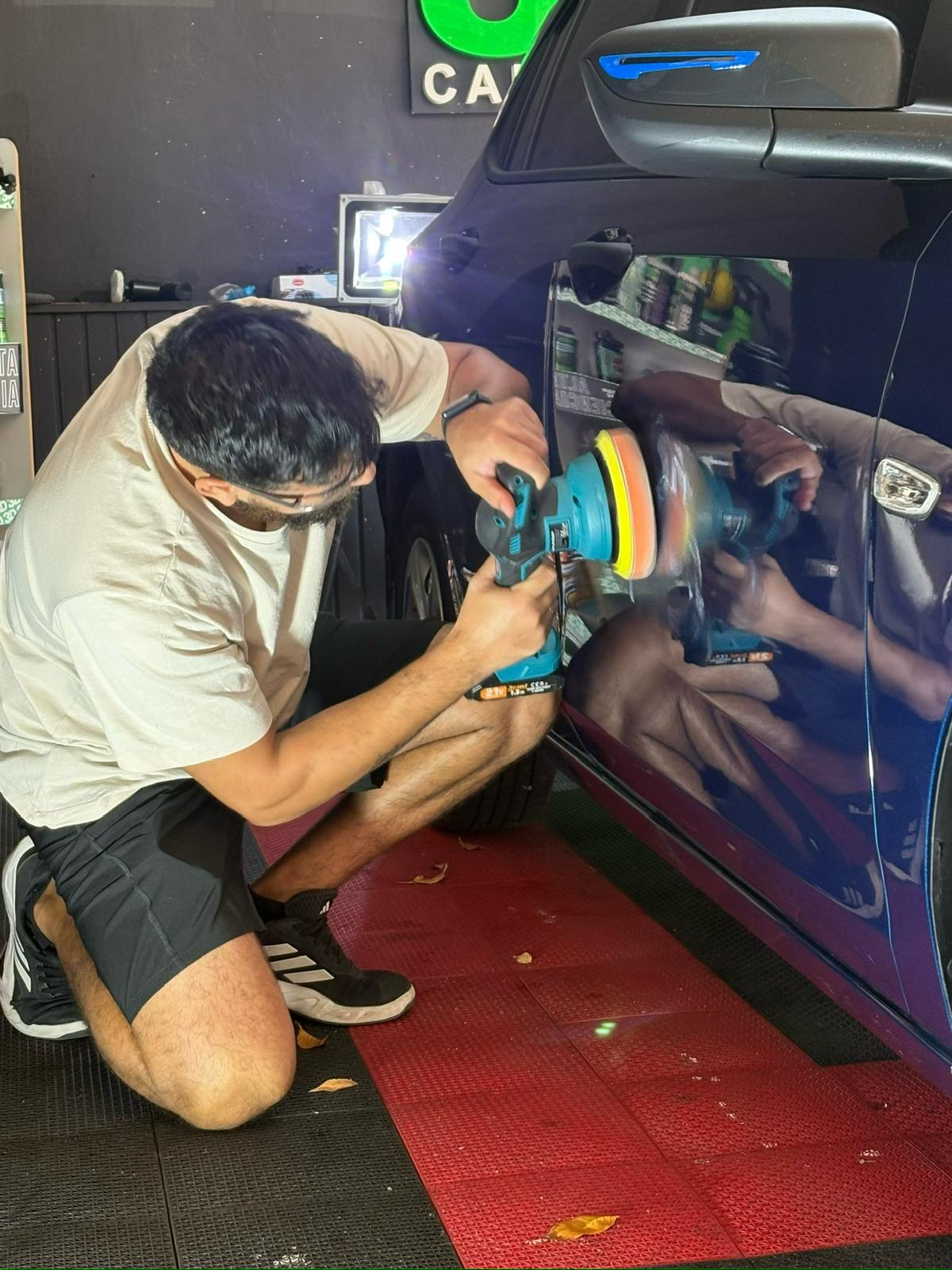 Pulido profesional sobre vehículo azul en el taller